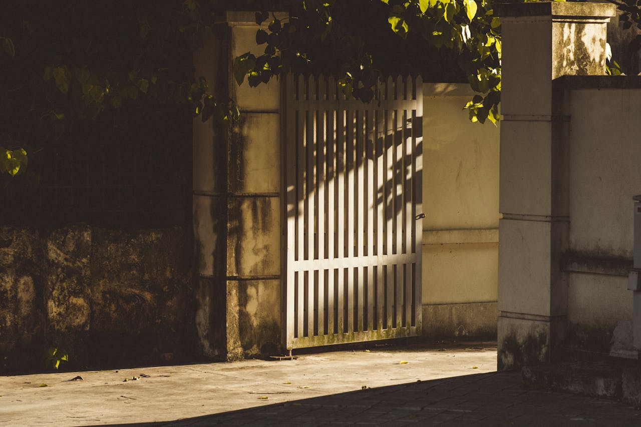 about-01 A tranquil scene featuring a white gate with surrounding shadows, creating an urban oasis.